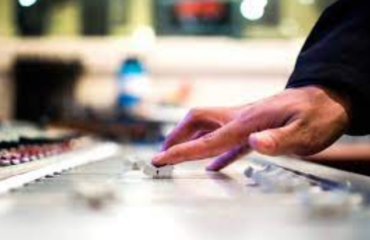 a hand moves a slider of an editing mixer in a recording studio