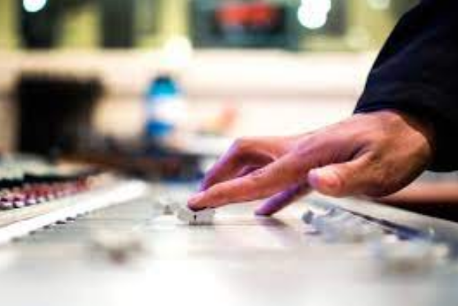 a hand moves a slider of an editing mixer in a recording studio