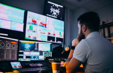 man sitting in front of plenty of computers and screens in recording studio