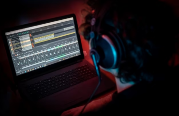 A man focused on his laptop, engaged in editing music using music editing software